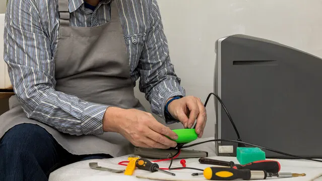 Technician testing an electronic component at a repair bench